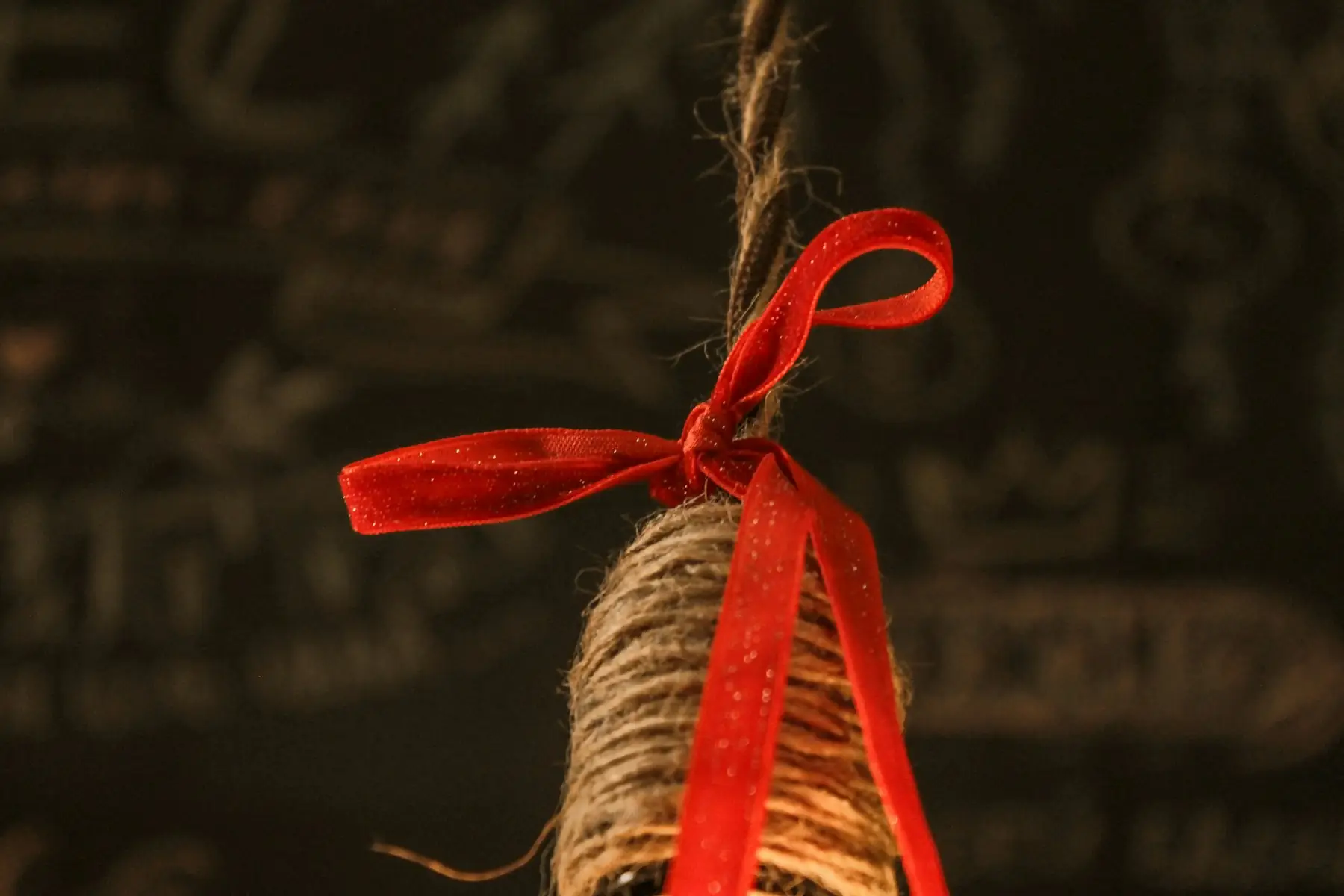A bottle neck wrapped in twine with a red ribbon bow