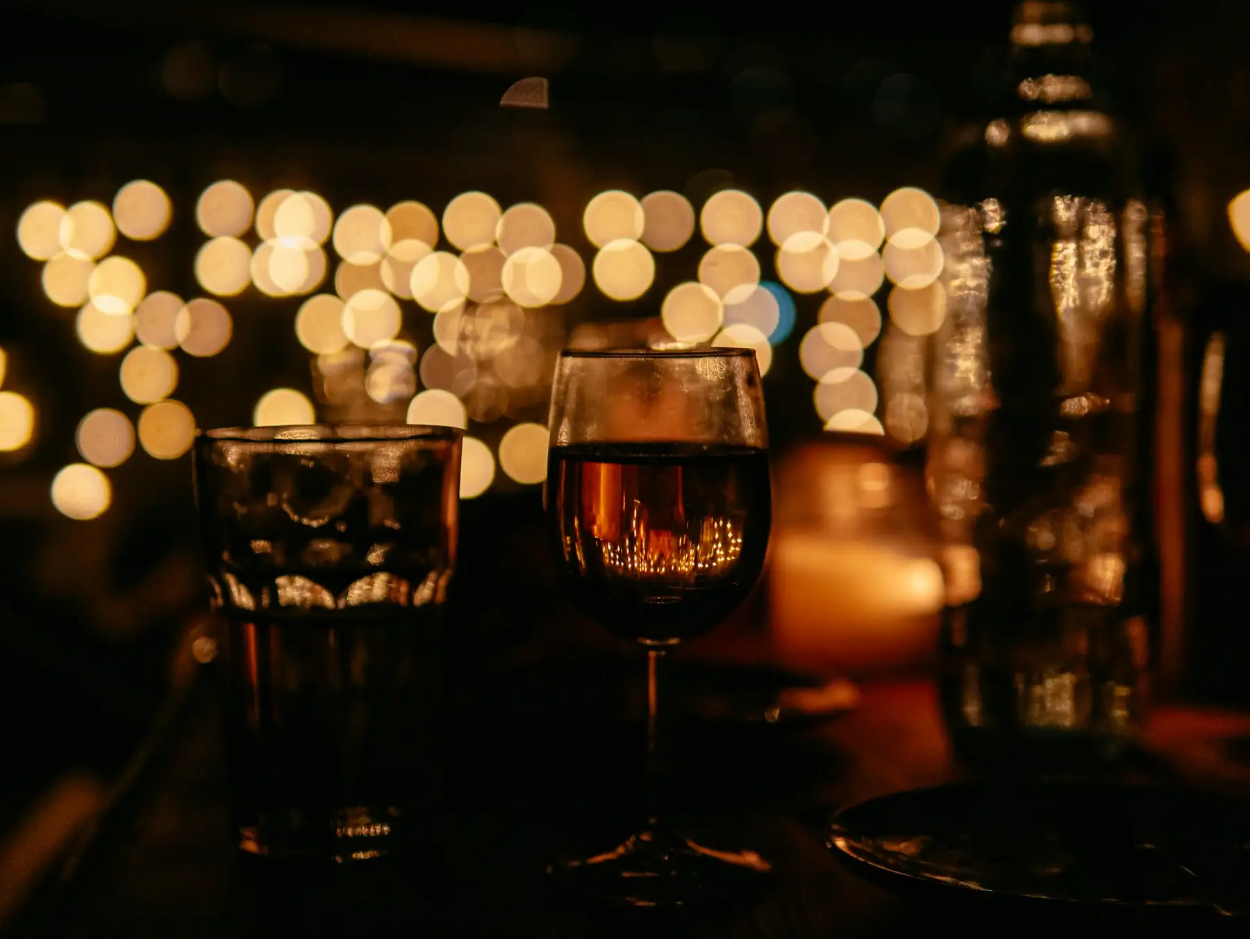 A wine glass on a bar with warm lights behind